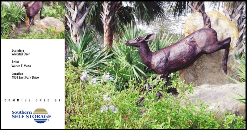 Bronze statue of a whitetail deer in grassy area